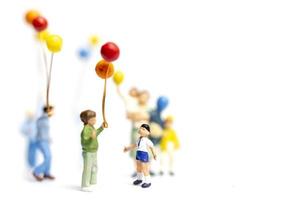 Niños en miniatura sosteniendo globos sobre un fondo blanco. foto