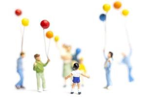 Miniature children holding balloons on a white background photo