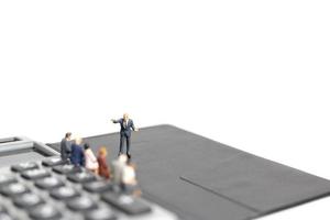 Miniature businessmen meeting on a calculator isolated on a white background, business and finance concept photo