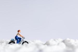 Miniature travelers riding bicycles in the snow, winter background concept photo