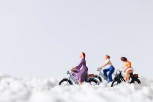 Miniature travelers riding bicycles in the snow, winter background concept photo