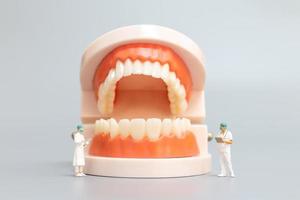 Dentista en miniatura que repara dientes humanos con encías y esmalte, concepto médico y de salud