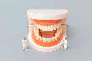 Miniature dentist repairing human teeth with gums and enamel, health and medical concept photo