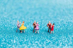 Miniature couples dancing on blue glitter background, Valentine's Day concept photo