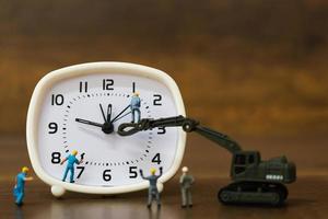 Miniature team working on an alarm clock, working time concept photo