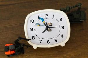 Equipo en miniatura trabajando en un reloj despertador, concepto de tiempo de trabajo foto