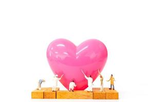 Gente en miniatura pintando un corazón rosa sobre un fondo blanco, feliz día de San Valentín concepto