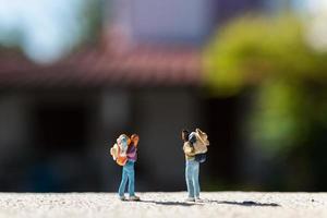 Miniature travelers with backpacks standing on a road, travel concept photo