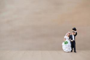 Miniature bride and groom on a wooden background photo