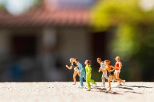 Grupo en miniatura de personas corriendo en una carretera de hormigón, concepto de estilo de vida saludable foto