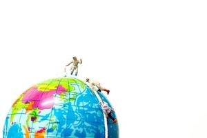 Miniature hikers climbing up on the globe, sport and leisure concept photo