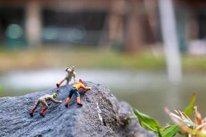 Miniature hikers climbing up on a rock, sports and leisure concept photo