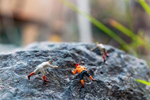Miniature hikers climbing up on a rock, sports and leisure concept photo