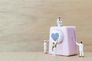 Miniature people painting a heart-shaped punching machine, Valentine's Day concept photo