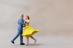 Miniature couple dancing on a wooden background, Valentine's Day concept photo