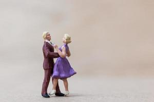 Pareja en miniatura bailando sobre un fondo de madera, concepto de día de San Valentín foto