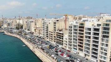 antenn 4k drönare som flyger mot ett tungt trafikerat område i ett kuststadsblock av sliema, ett tätbefolkat medelhavssamhälle på ön Malta. video