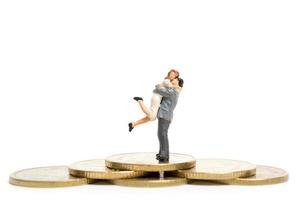 Miniature couple hugging on a stack of coins, money and financial concept photo