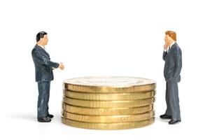 Miniature businessmen standing on a stack of coins, money and financial concept photo