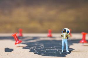 Miniature backpacker walking on a world map, tourism and travel concept photo