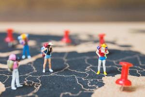 Miniature backpackers walking on a world map, tourism and travel concept