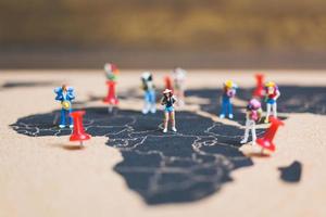 Miniature backpackers walking on a world map, tourism and travel concept photo