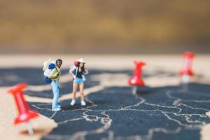 Mochileros en miniatura caminando sobre un mapa del mundo, concepto de turismo y viajes foto