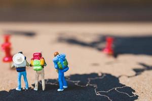 Miniature backpackers walking on a world map, tourism and travel concept