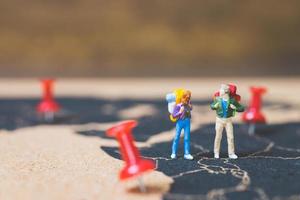 Miniature backpackers walking on a world map, tourism and travel concept photo