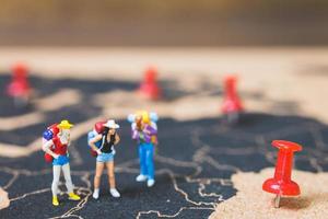 Miniature backpackers walking on a world map, tourism and travel concept photo