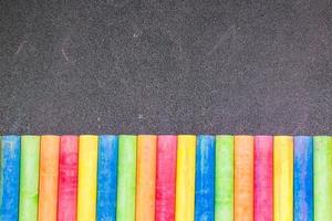 Row of rainbow colored chalk on a blackboard photo