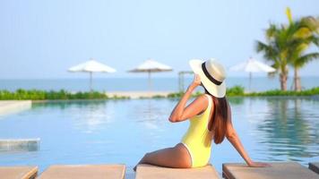 Mujer vacaciones de ocio alrededor de la piscina cerca de la playa del mar