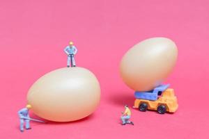 Miniature people working on Easter-eggs for Easter photo