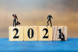Miniature divers diving around wooden blocks with the number 2021, Happy New Year concept photo
