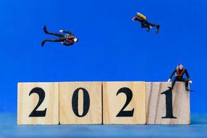 Miniature divers diving around wooden blocks with the number 2021, Happy New Year concept photo