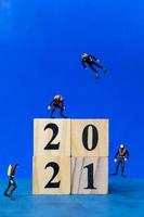 Miniature divers diving around wooden blocks with the number 2021, Happy New Year concept photo