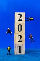 Miniature divers diving around wooden blocks with the number 2021, Happy New Year concept photo