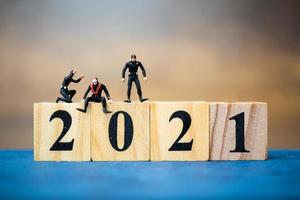 Miniature divers diving around wooden blocks with the number 2021, Happy New Year concept photo