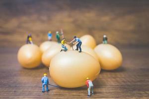 Miniature people working on Easter-eggs for Easter photo