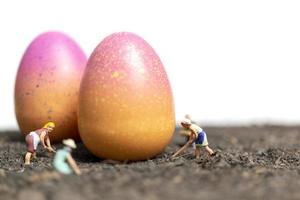 Miniature people working on Easter-eggs for Easter photo