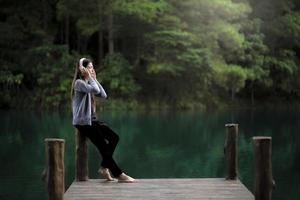 Woman relaxing near on a dock listening to music photo