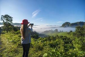 Woman traveler taking photos of mountains