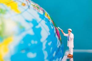 Miniature painter painting on a globe, Earth Day concept photo