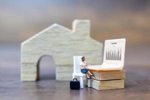 Miniature person working on a computer laptop, work at home concept photo