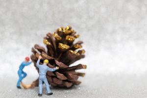 Miniature workers teaming up to prepare a Christmas pine cone, Christmas and Happy New Year concept photo