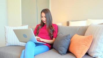 Mujer usa computadora portátil para trabajar en el sofá video