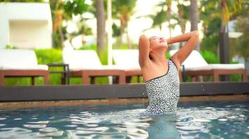 Mulher asiática relaxando na piscina no resort video