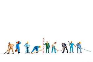 Miniature workers standing on a white background, labor concept photo