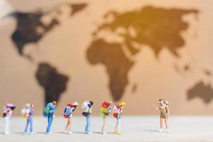 Miniature travelers walking on a world map, traveling and exploring the world concept photo