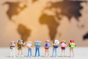 Miniature travelers walking on a world map, traveling and exploring the world concept photo